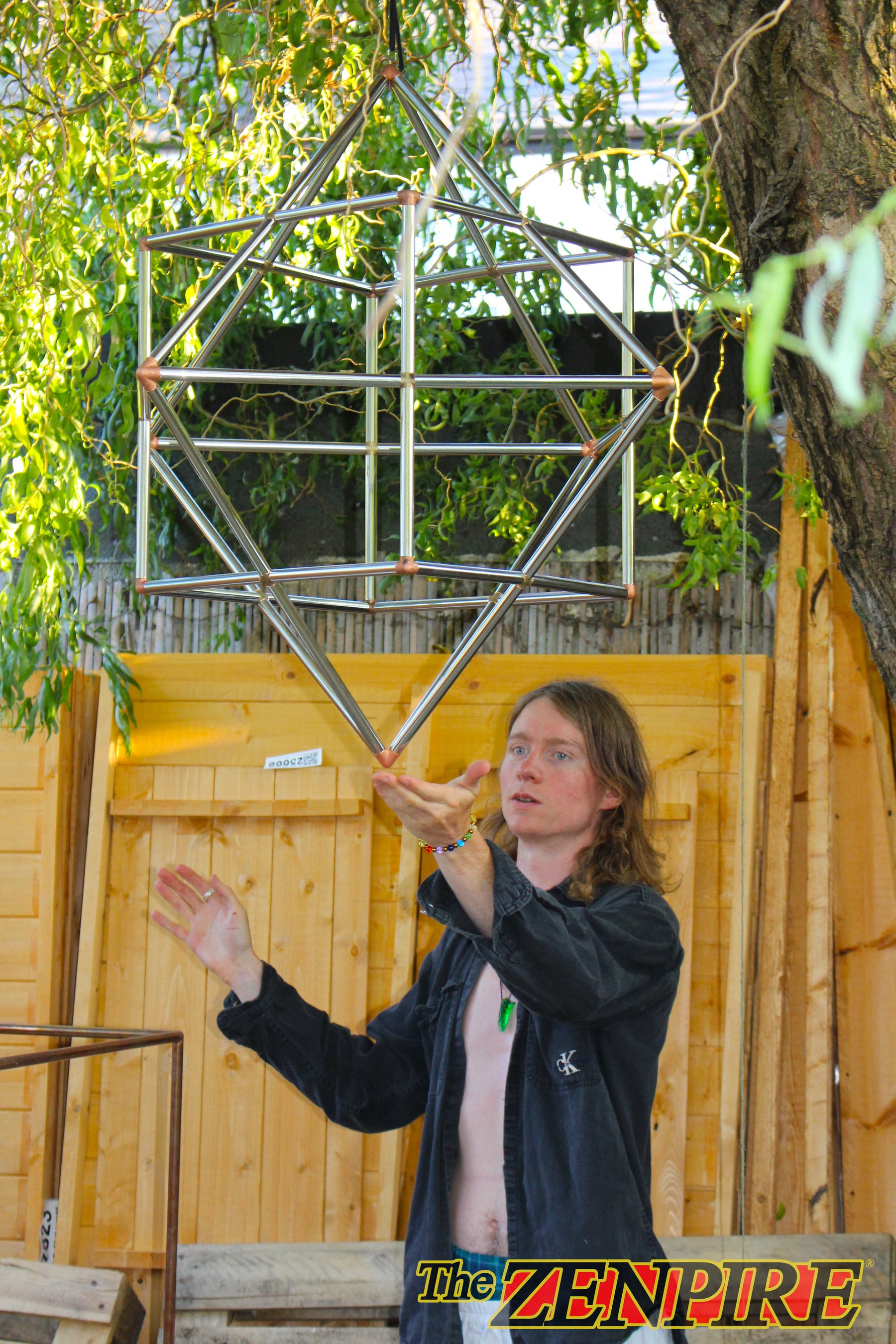 The King of The Zenpire man standing communing with his sacred geometric copper wire form of cube-otcahedron