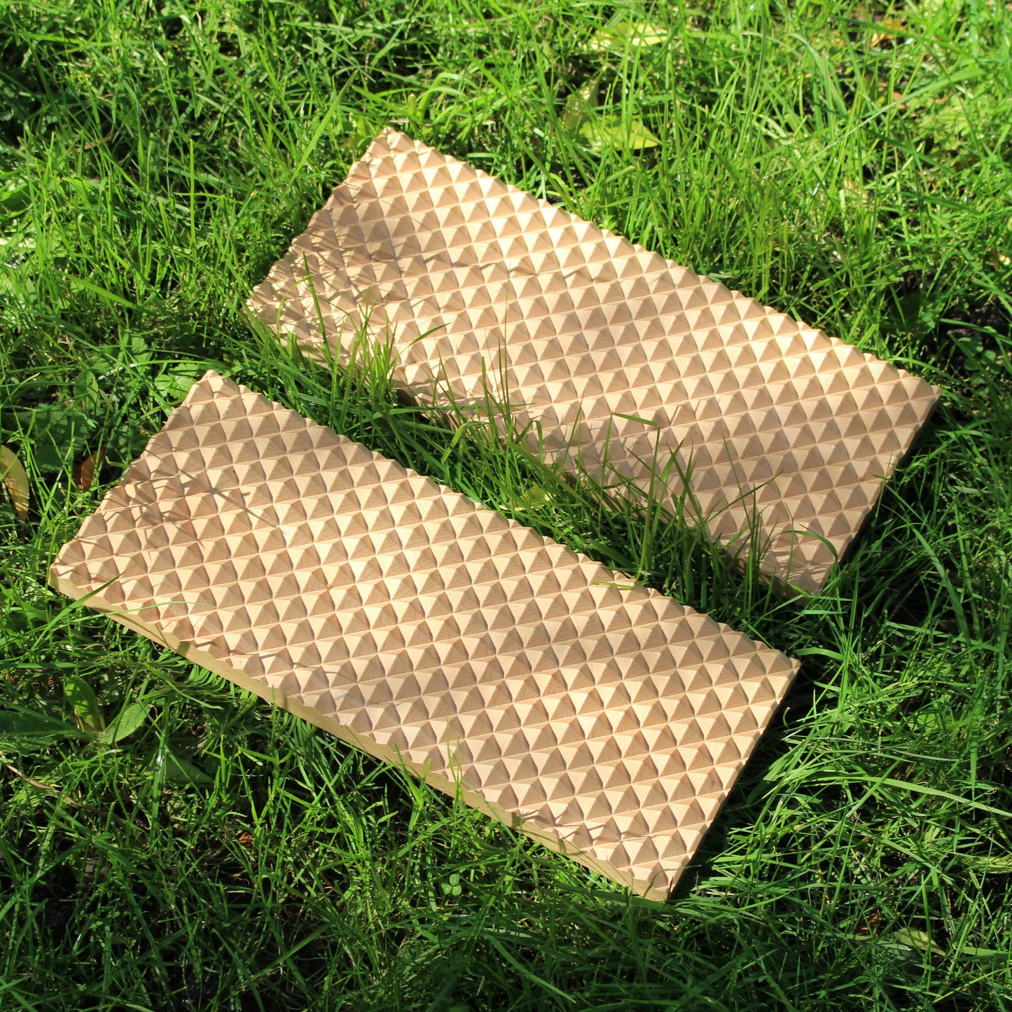 a beech wood spiked sadhu acupressure board laid out in grass