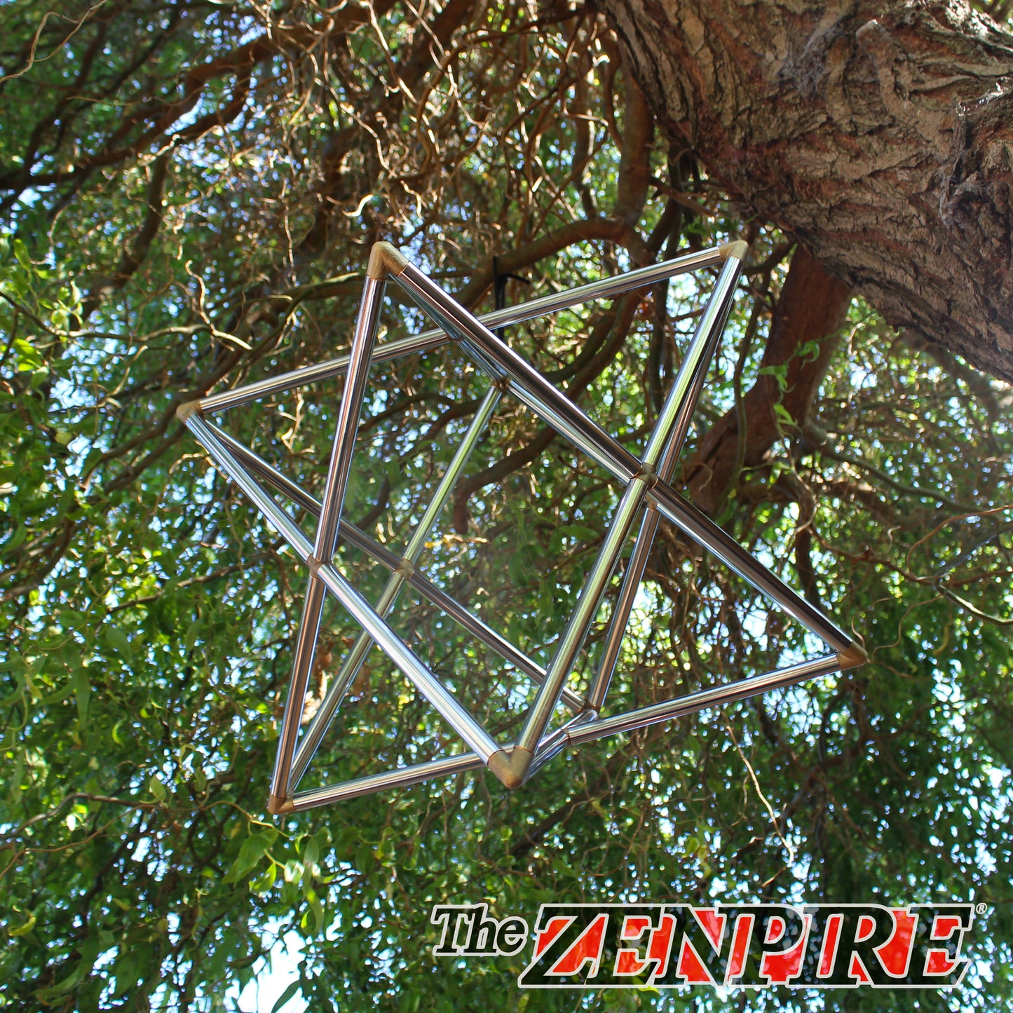 A stunning metallic chrome copper merkaba pyramid hanging from a tree, for meditation and self healing
