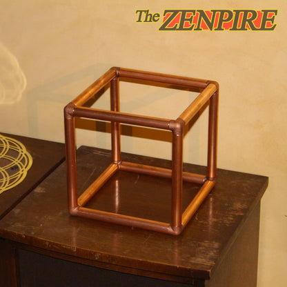 A geometric cube-shaped metal frame stand made of copper pipes