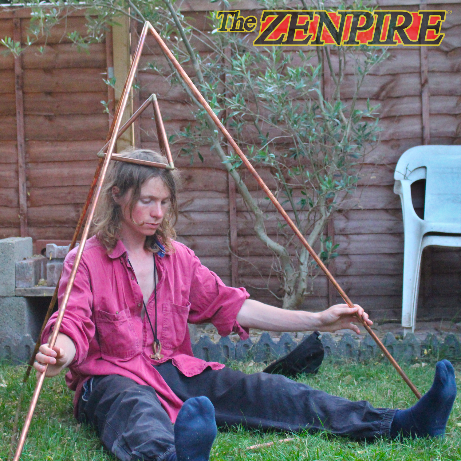 person meditating doing yoga in copper healing tetrahedron with copper tetrahedron balanced on his head