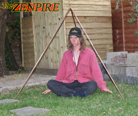 person sitting inside copper healing pyramid tetrahedron kit on grass