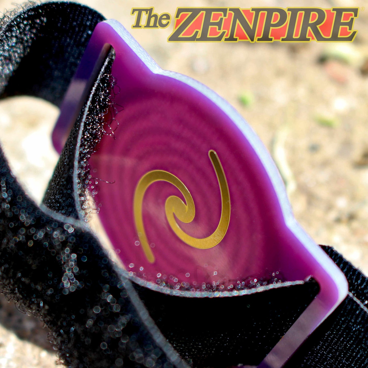A close-up of a black wristband with a translucent purple and magenta visor featuring a gold krystal spiral