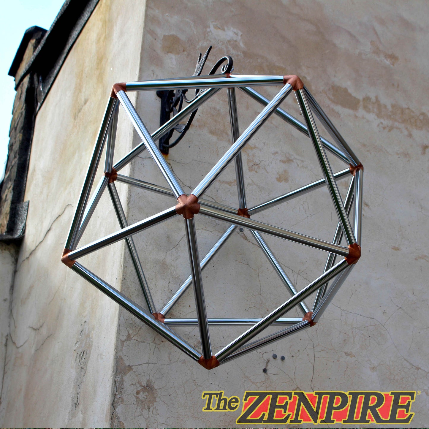 a geometric icosahedron structure made from chrome plated copper pipe, hanging from a wall, used for meditation and spiritual healing.